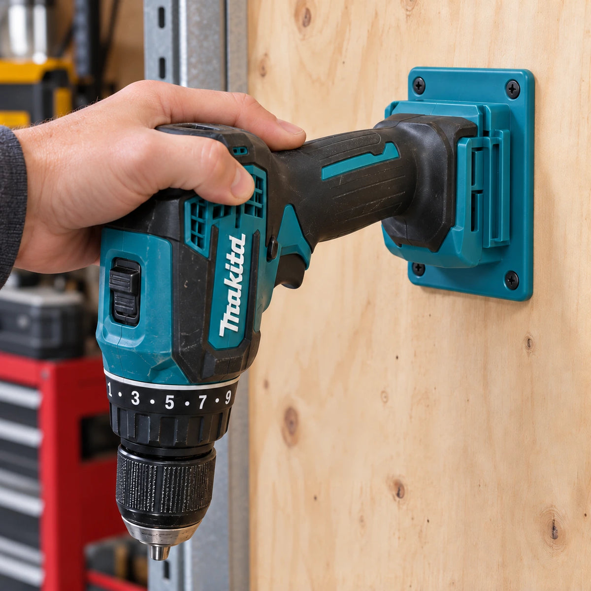 Une main glisse une perceuse-visseuse Makita dans un support turquoise par son logement de batterie